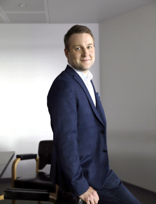 Teknologiateollisuuden johtaja, pääekonomisti Petteri Rautaporras nojaa tuoliin sinisessä puvussa, vaaleaseinäisessä huoneessa.