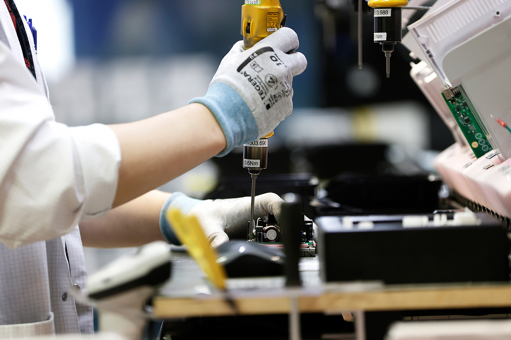 Tehtaassa työskentelevän henkilön kädet, kuvituskuva.