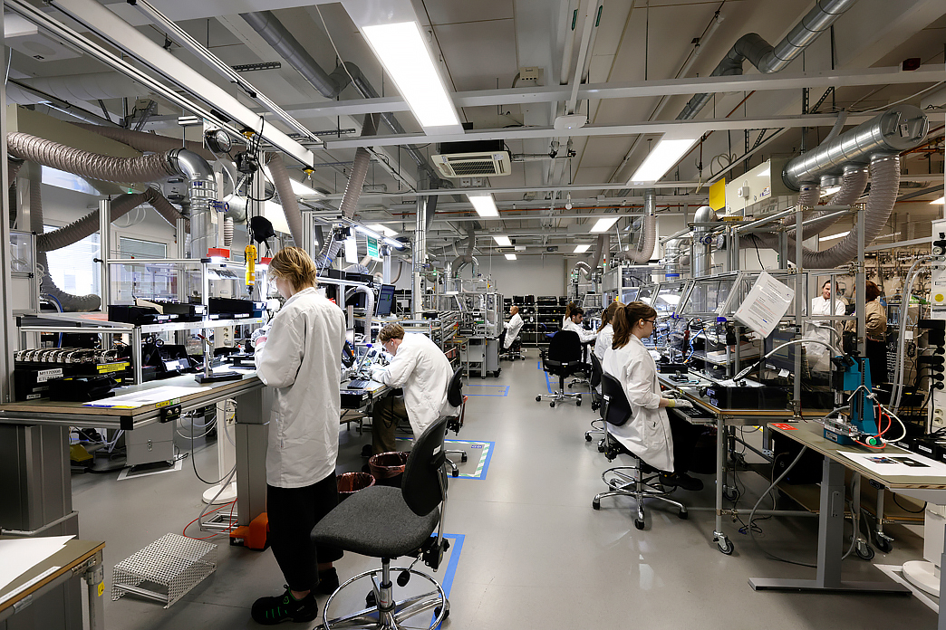 Henkilöitä työpisteidensä ääressä tehtaassa, kuvituskuva.