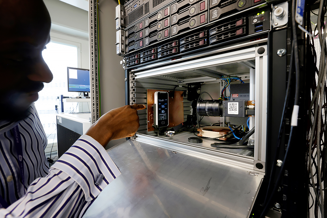 Henkilö osoittaa sormellaan laitetta, jossa paljon osia, kuvituskuva.