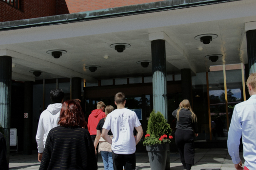 Nuoria kävelemässä Aalto-yliopiston ovista sisään.