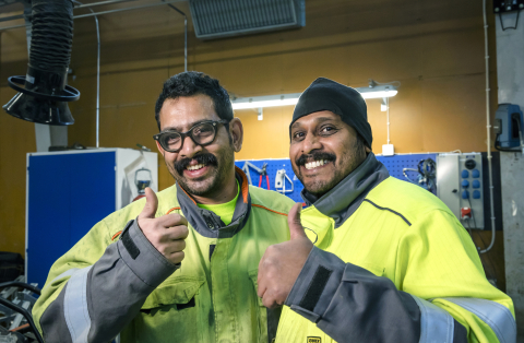 Tormets Oy:n työntekijät Johny Jackson ja Sarathlal Mohanlal hymyilevät kuvassa keltaiset työtakit päällä. 