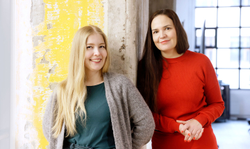 Siili solutionsin luottamushenkilö Maija Apunen ja henkilöstöjohtaja Taru Salo seisovat vierekkäin toimistossa ja hymyilevät.