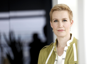 Teknologiateollisuuden veroasiantuntija Maria Volanen seisoo mustaa taustaa vasten vaaleanvihreässä jakussa.