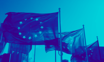 EU-lippuja liehumassa taivasta vasten siniseksi värjätyssä kuvassa
