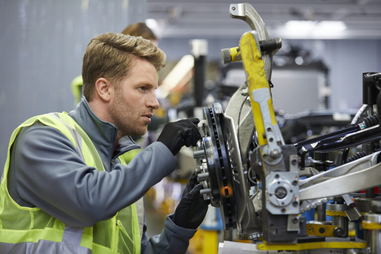 Confident mid adult engineer examining car chassis at automobile
