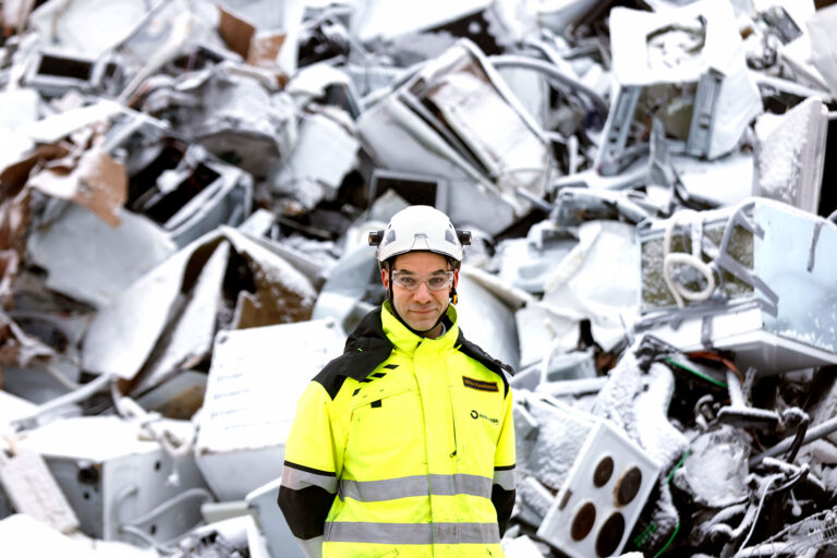 Kuusakosken toimitusjohtaja Mikko Kuusilehto turvavarusteet päällä romukasan edessä.