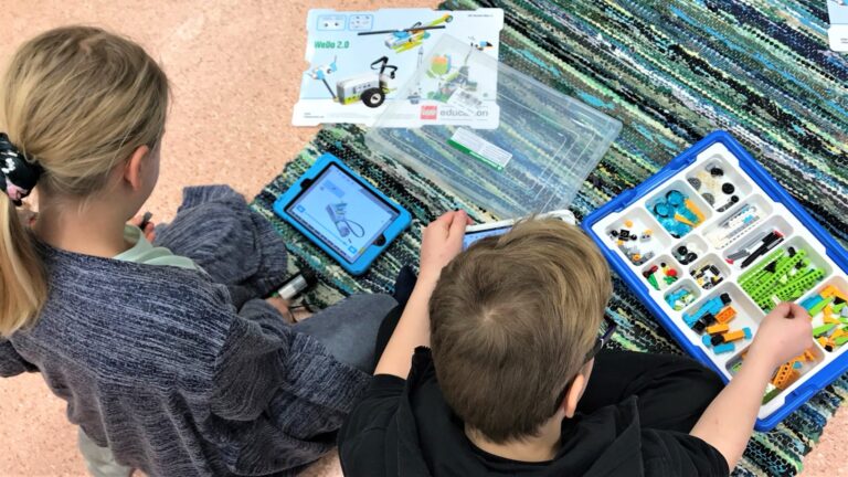 Lapsia rakentamassa pientä robottia legoista ohjeiden avulla.
