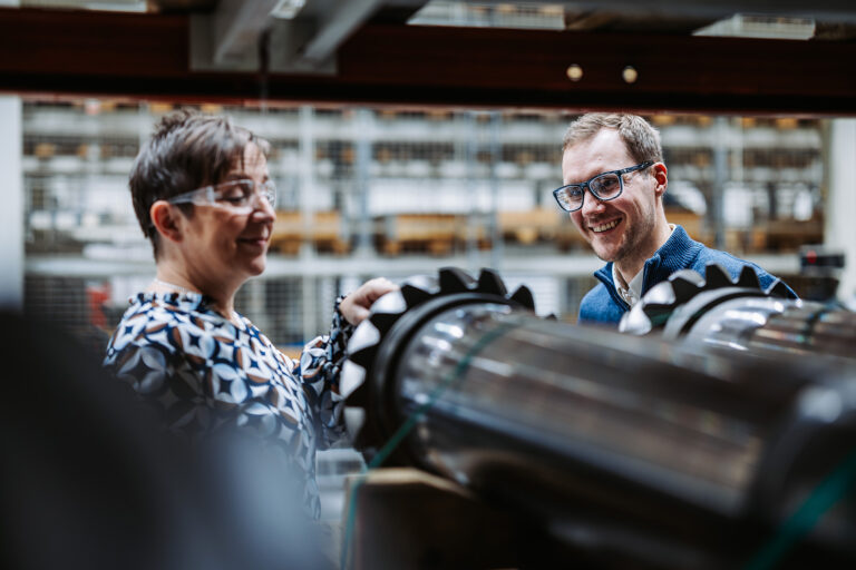 Nainen ja mies tarkastelevat hammaspyörää.