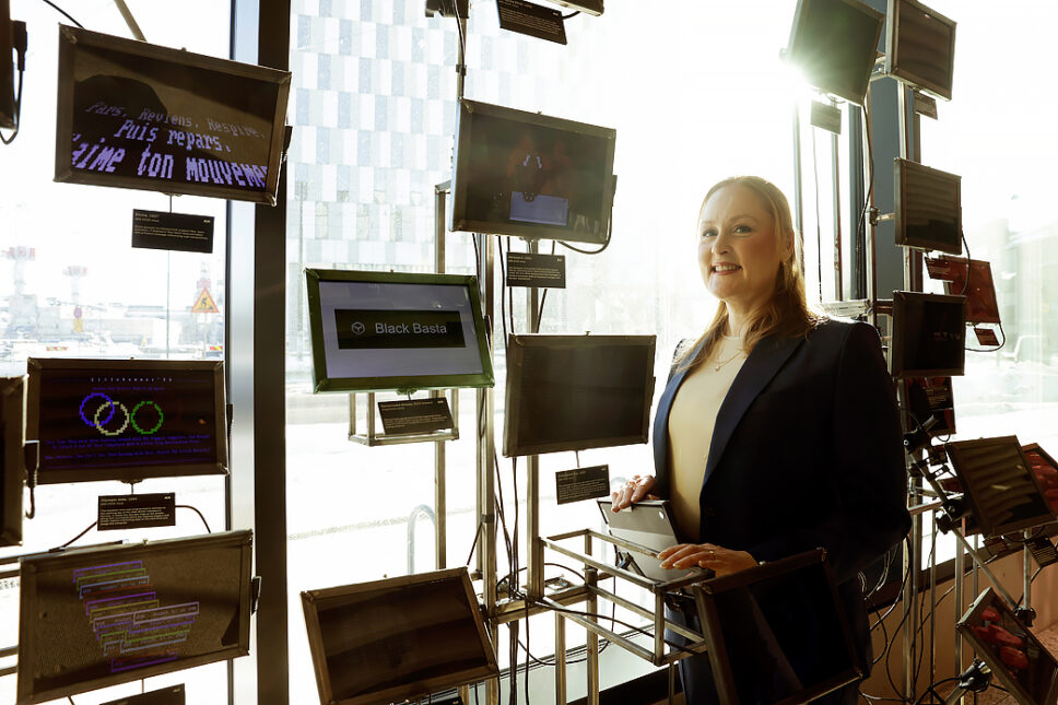 Nainen ikkunan edessä erilaisten pienten näyttöjen vieressä.