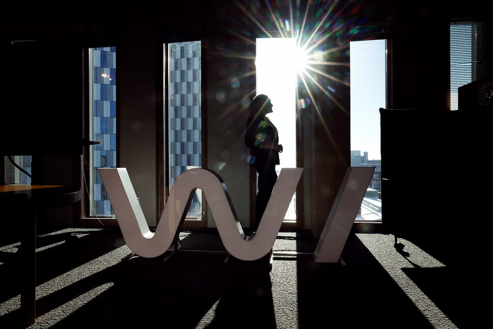 Nainen ikkunan edessä seisomassa auringon paisteessa.