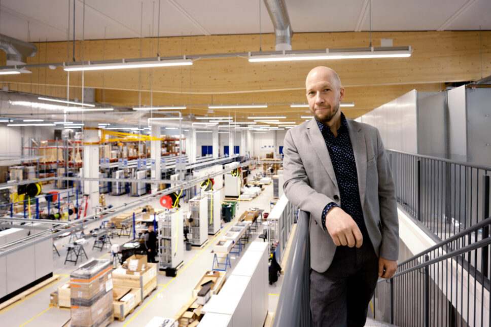 Mies nojaa portaikon kaiteeseen takanaan tehdas- ja varastotiloja.