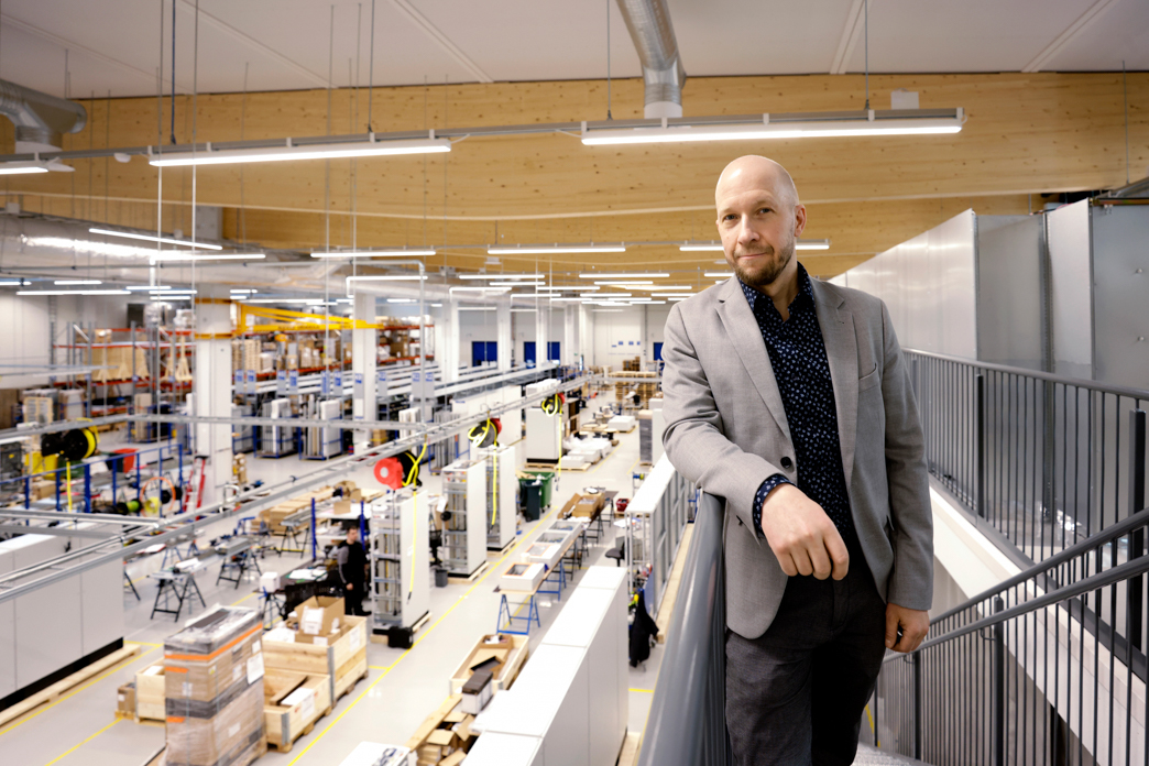 Mies nojaa portaikon kaiteeseen takanaan tehdas- ja varastotiloja.
