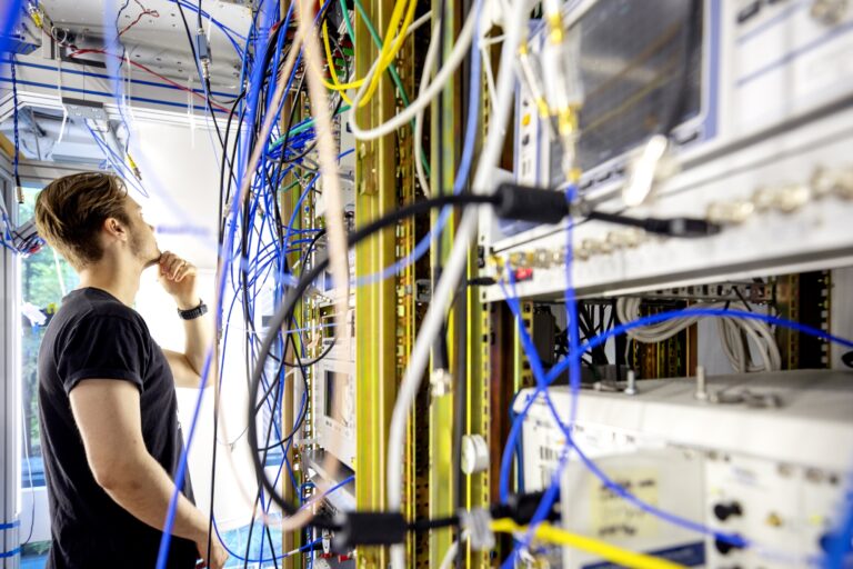 Henkilö katso pohtien erivärisiä johtoja.